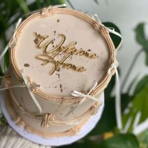 Personalised acrylic cake charm with custom name in gold.