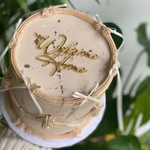 Personalised acrylic cake charm with custom name in gold.